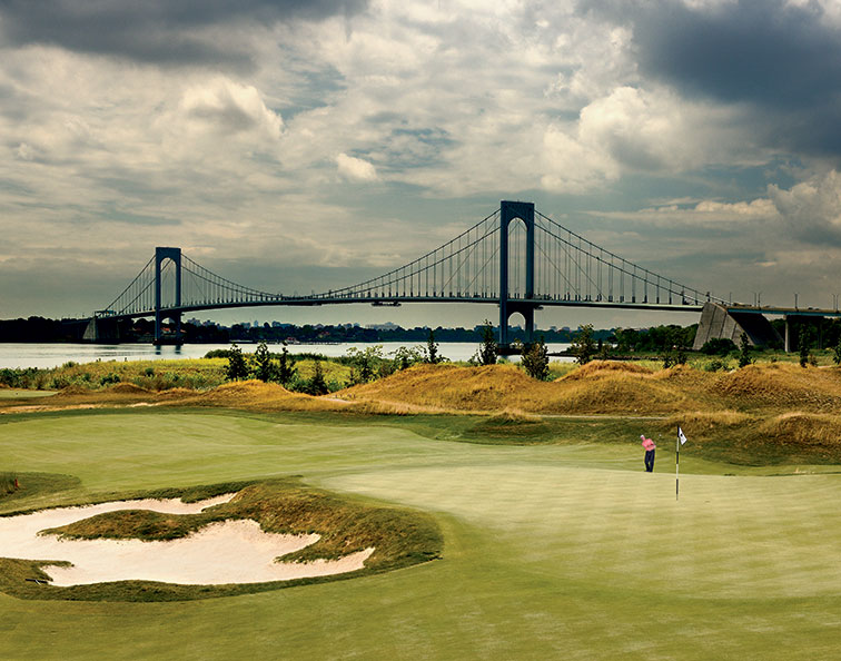 With the Whitestone Bridge in the background, Michael Breed chips on the 17th hole at Trump Golf Links at Ferry Point in New York City.