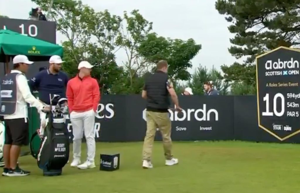 A stunned Rory McIlroy watches spectator take a club from his bag, pretend to hit tee shot